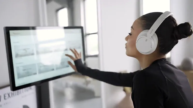 Cliente avec casque devant le kiosque tactile de son poste