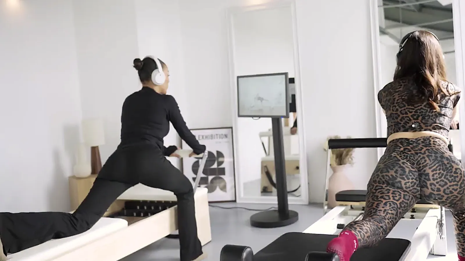 Deux clientes en séance de Pilates Reformer guidée sur écran, en autonomie